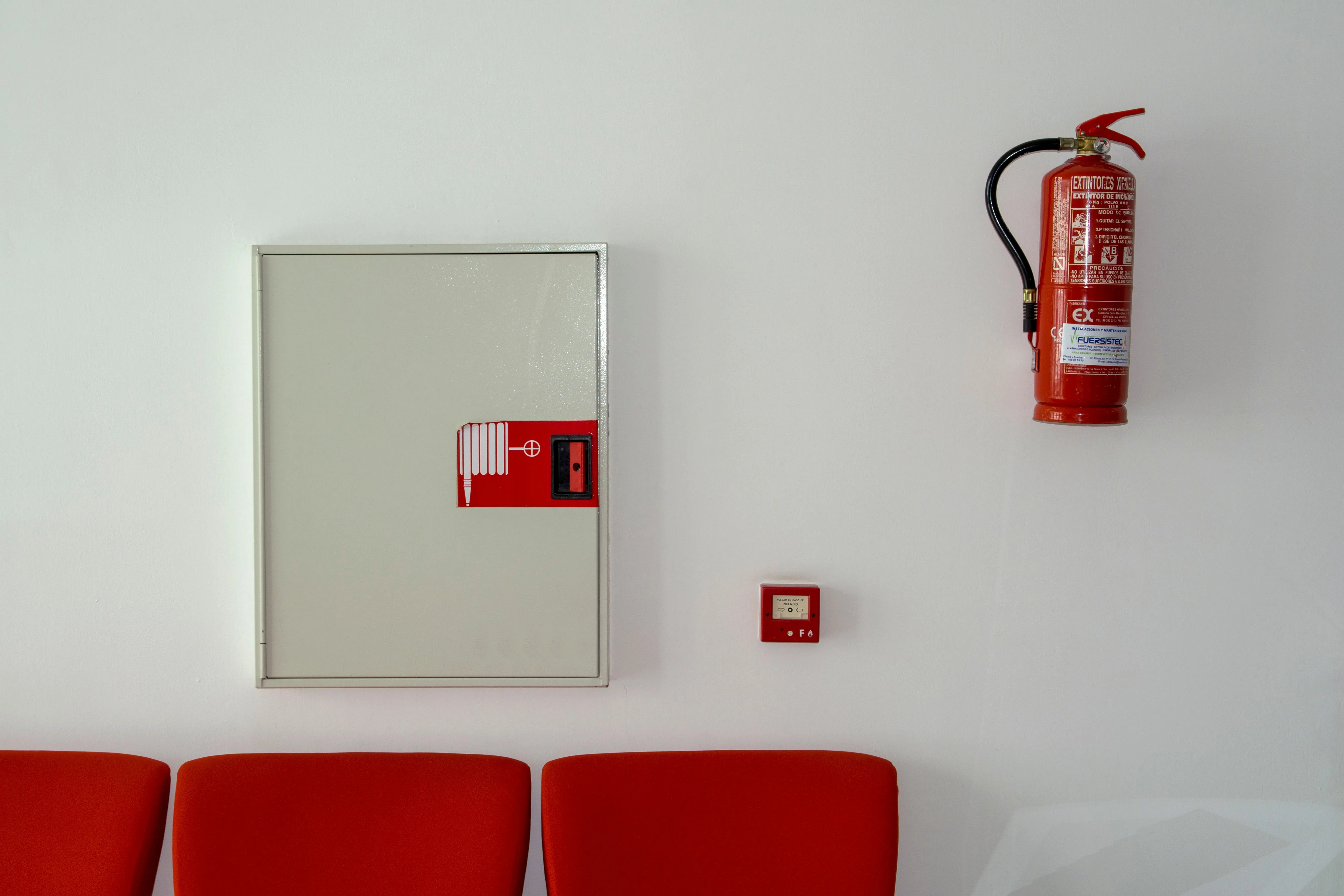 Feuerlöscher und Wandhydrant-Schrank an einer Wand